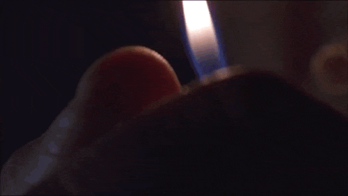 a person is lighting a cigarette with a lighter in the dark