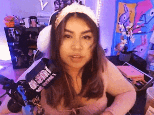 a woman wearing a headband and ear muffs is standing in front of a microphone .
