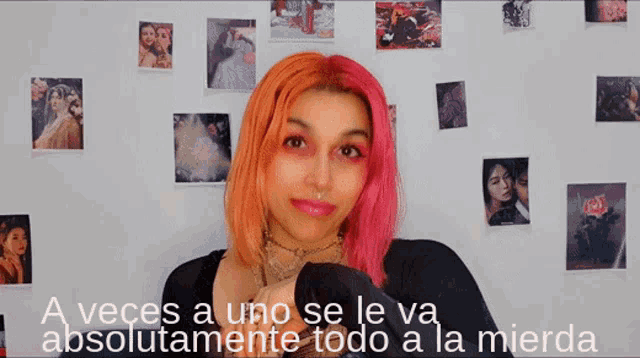 a woman with pink hair is standing in front of a wall with pictures and the words a veces a uno