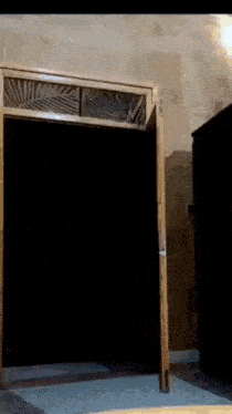 a dark room with a wooden door and a light shining through it