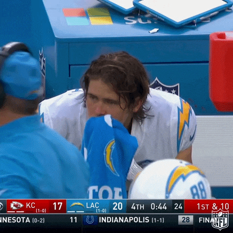 a football player wipes his nose with a blue towel during a game