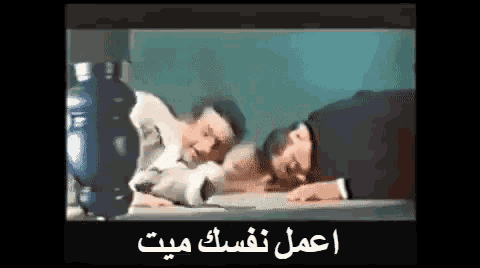 a group of men are sitting at a table with arabic writing on the screen