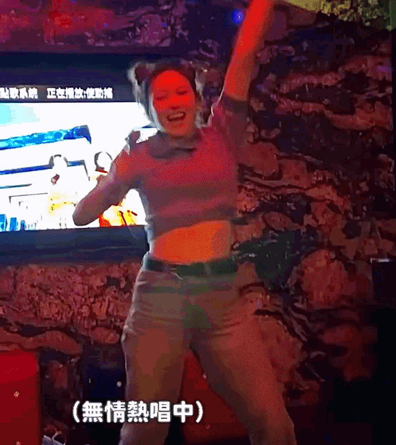 a woman dancing in front of a tv with chinese writing