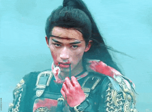 a man with blood on his face is holding a stick in his mouth