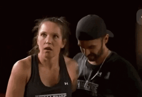 a man and a woman are standing next to each other and the woman is wearing a challenge tank top