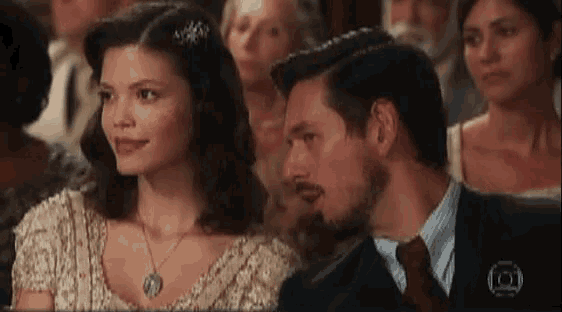 a man and woman are sitting next to each other in a crowd .