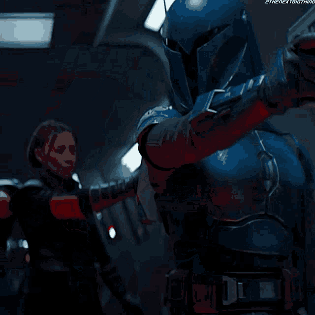 a man in a blue armor is pointing a gun at another man in a black armor