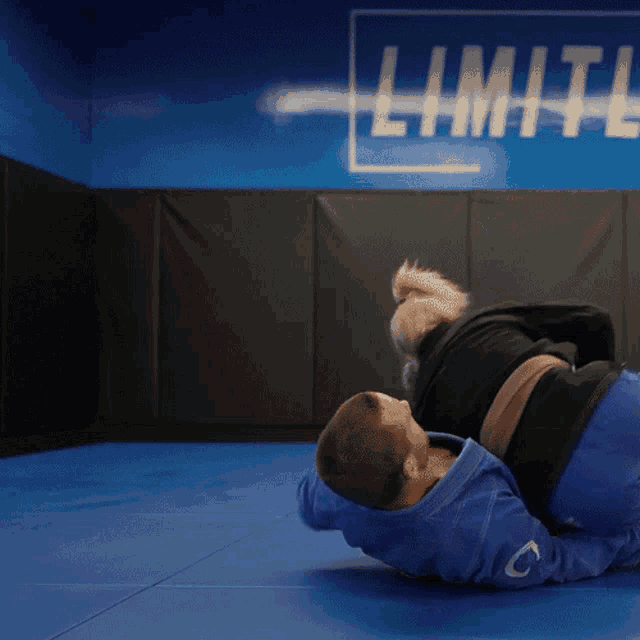 two men are wrestling in front of a sign that says limits