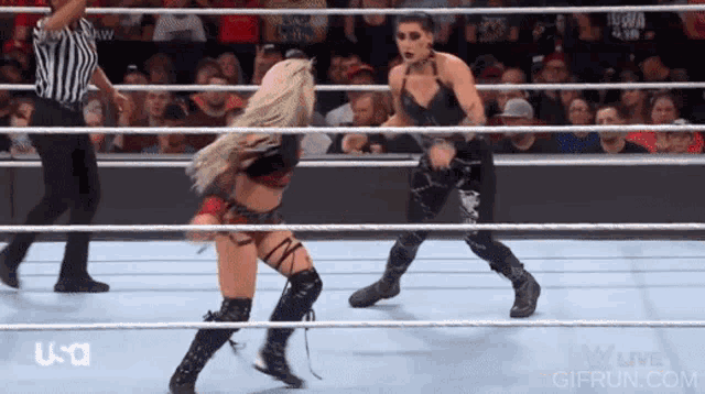two women are wrestling in a wrestling ring with a referee watching .