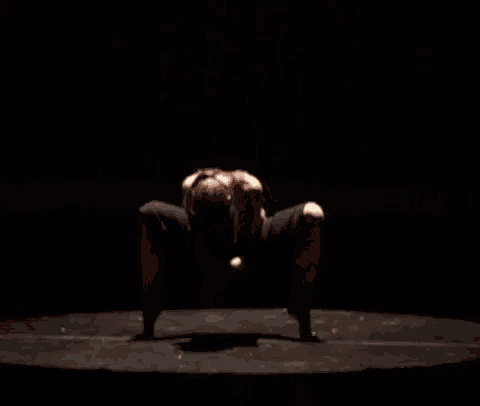a woman in a red shirt and black shorts is kneeling on a stage
