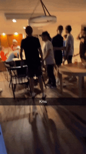 a group of people are gathered in a room with kms written on the bottom