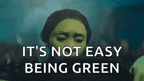 a woman wearing a green mask is crying and says `` it 's not easy being green '' .