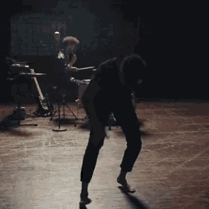 a man is dancing on a stage in front of a drum set
