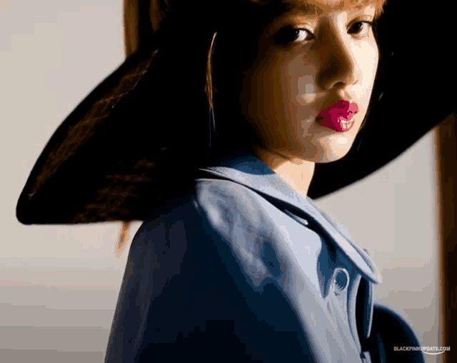 a woman wearing a blue coat and a black hat with the website blackpinkupdates.com written on the bottom