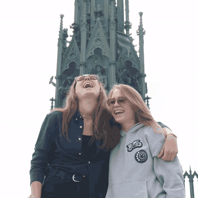 two girls are laughing in front of a tower and one has a hoodie that says ' rights ' on it