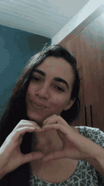 a woman making a heart with her hands in front of her face