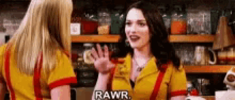 two women are standing next to each other in a kitchen and one of them is talking to the other .