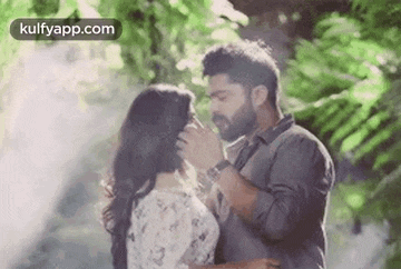 a man and a woman are kissing each other in a forest .