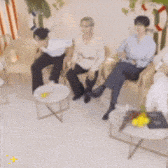 a group of people are sitting around a table in a living room