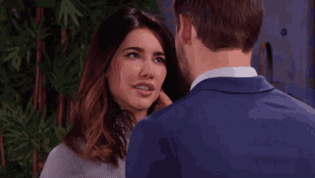 a man in a suit and a woman in a sweater are looking into each other 's eyes .
