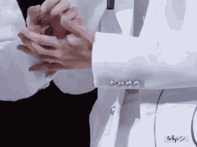 a man in a white jacket holds another man 's hand with a blue sticker that says ' pop ' on it
