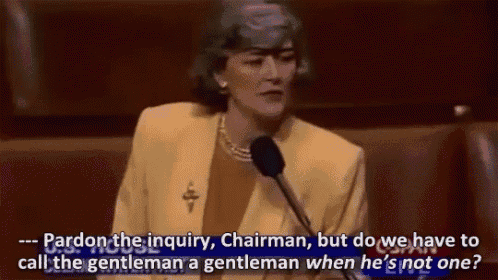 a woman in a yellow suit is speaking into a microphone and asking pardon