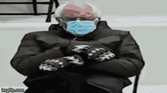bernie sanders is wearing a face mask and mittens while sitting in a chair .