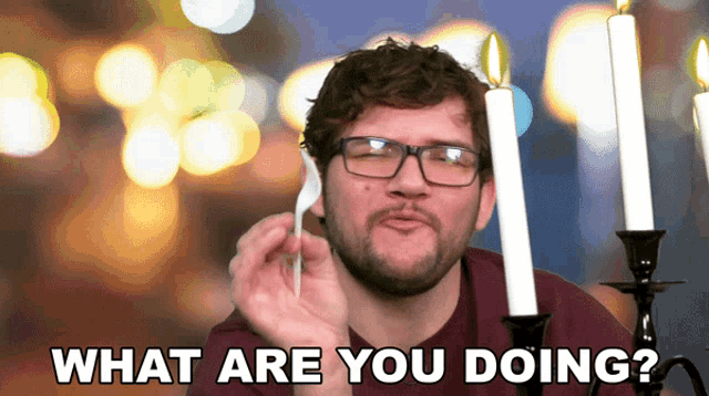 a man with glasses holds a fork in front of candles and the words what are you doing