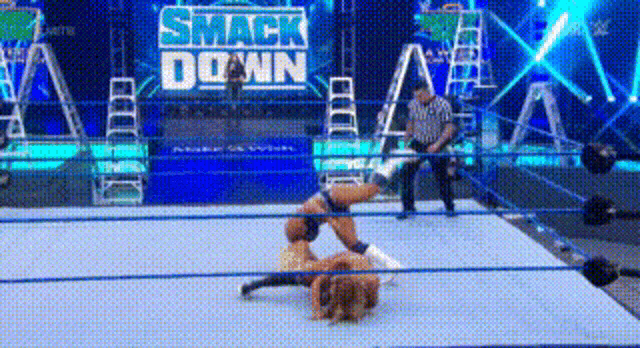 a woman is wrestling in a wrestling ring with a referee watching .