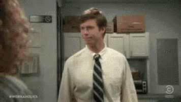 a man in a white shirt and tie is standing in a kitchen talking to a woman .