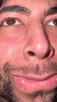 a close up of a man 's face with a beard and red eyes .