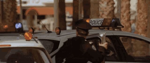 a police officer stands in front of a car with a police sign on top of it