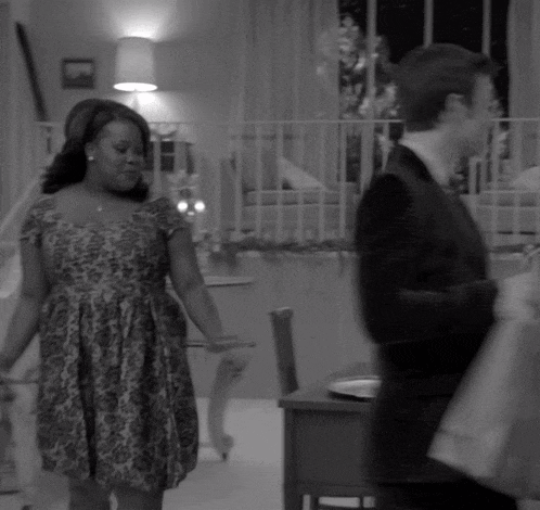 a woman in a dress stands next to a man in a suit in a black and white photo