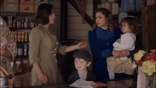 a woman in a blue coat is holding a child in front of a sign that says super ginger