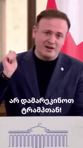 a man in a suit is giving a speech in a foreign language while standing in front of a podium .