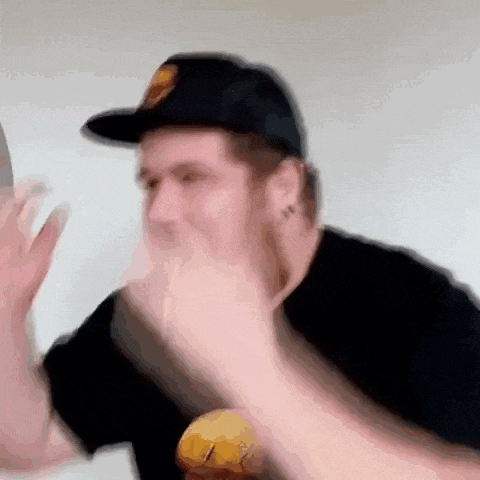 a man wearing a black hat and a black shirt is making a funny face .