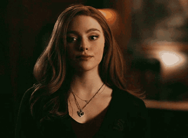 a woman with red hair wearing a black shirt and a necklace