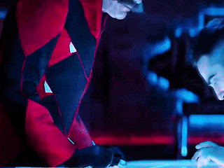 a man in a red jacket is looking down at something