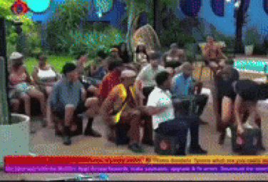 a group of people are sitting around a table in front of a tv screen that says ' breaking news '