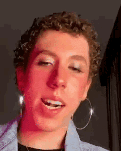 a close up of a person wearing hoop earrings and makeup
