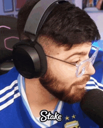 a man with a beard wearing headphones and glasses says " stake "