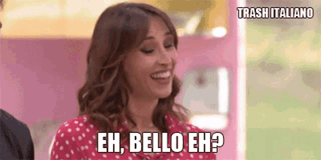 a woman in a red polka dot shirt is laughing and asking eh bello eh ?