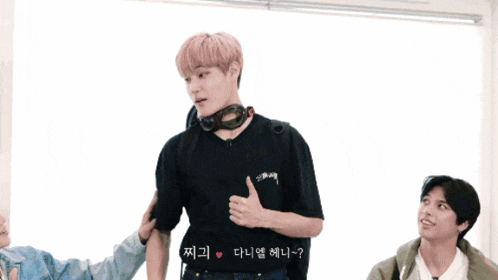 a man wearing a black stussy t-shirt is giving a thumbs up