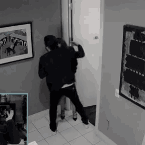 a man and a woman are standing in a hallway with a picture on the wall that says ' a ' on it