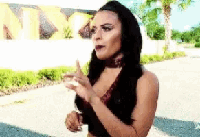 a woman with long black hair is standing in front of a sign that says nxt on it .