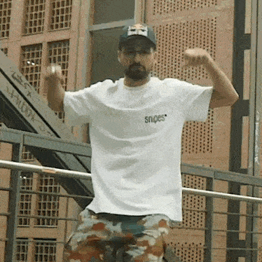 a man wearing a white snipes t-shirt and a red bull hat