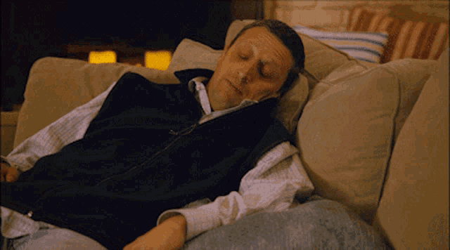 a man sleeping on a couch with his eyes closed