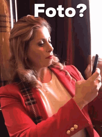 a woman in a red jacket is looking at her phone with the words foto written above her