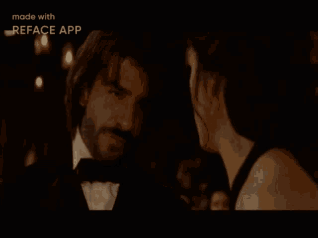 a man in a tuxedo and a woman in a black dress are looking at each other