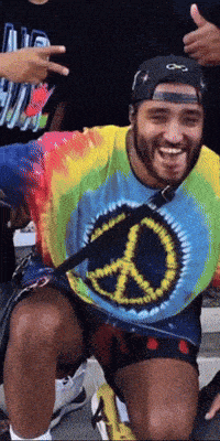 a man wearing a tie dye shirt with a peace sign on it is smiling
